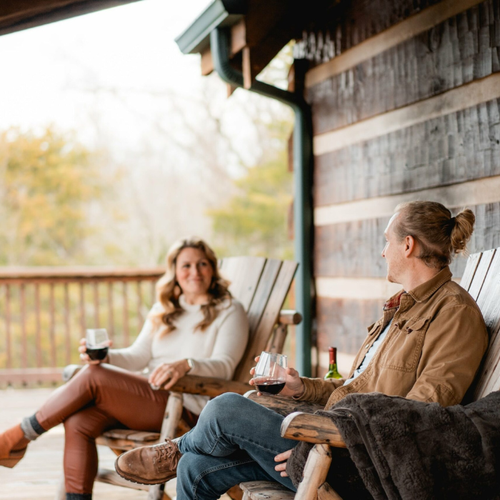 Photo of a young male and female couple enjoying a drink on a cabin porch in jefferson county tn